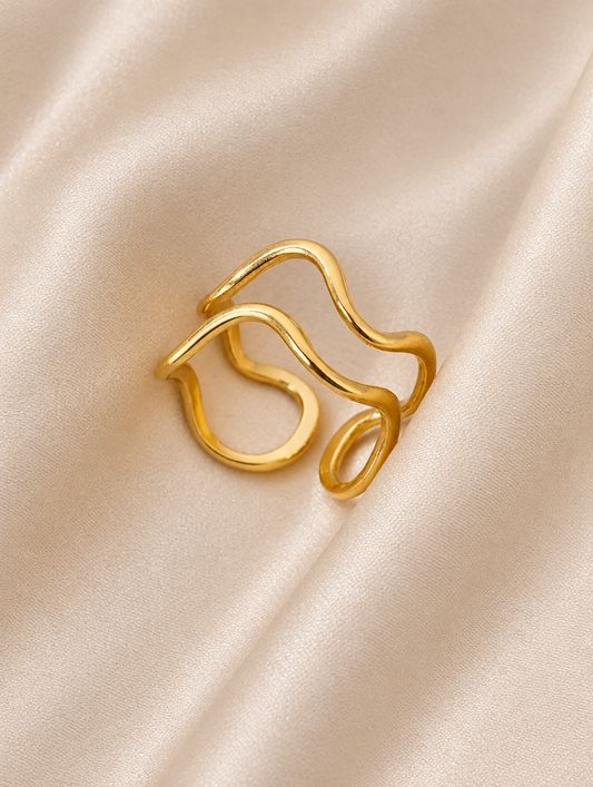 Gold swirl loop open ring resting on a soft textured surface