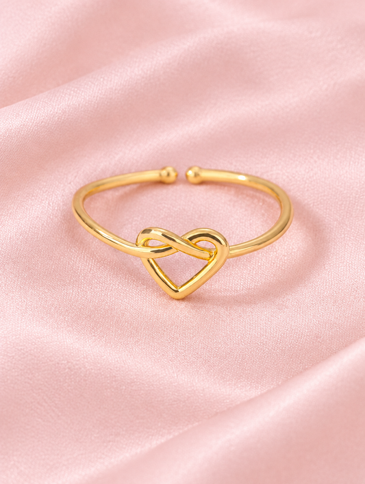 Gold open heart ring resting on a soft textured surface