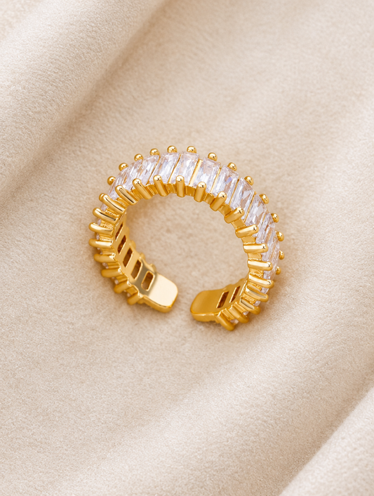 Gold baguette clear stone ring resting on a soft textured surface