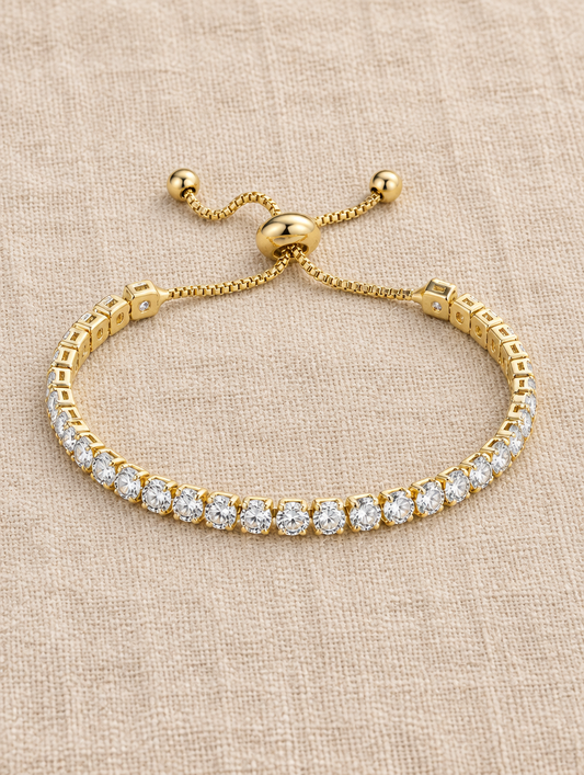 Gold slider tennis bracelet with round stones on beige linen