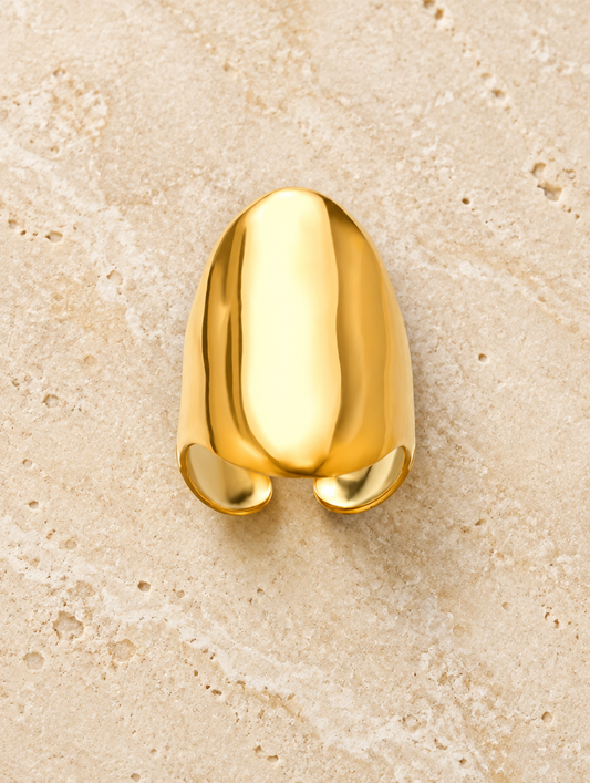 Gold smooth saddle ring resting on a soft textured surface