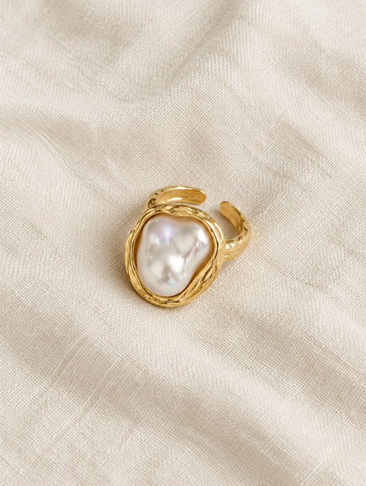 Gold textured baroque pearl ring resting on a soft textured surface