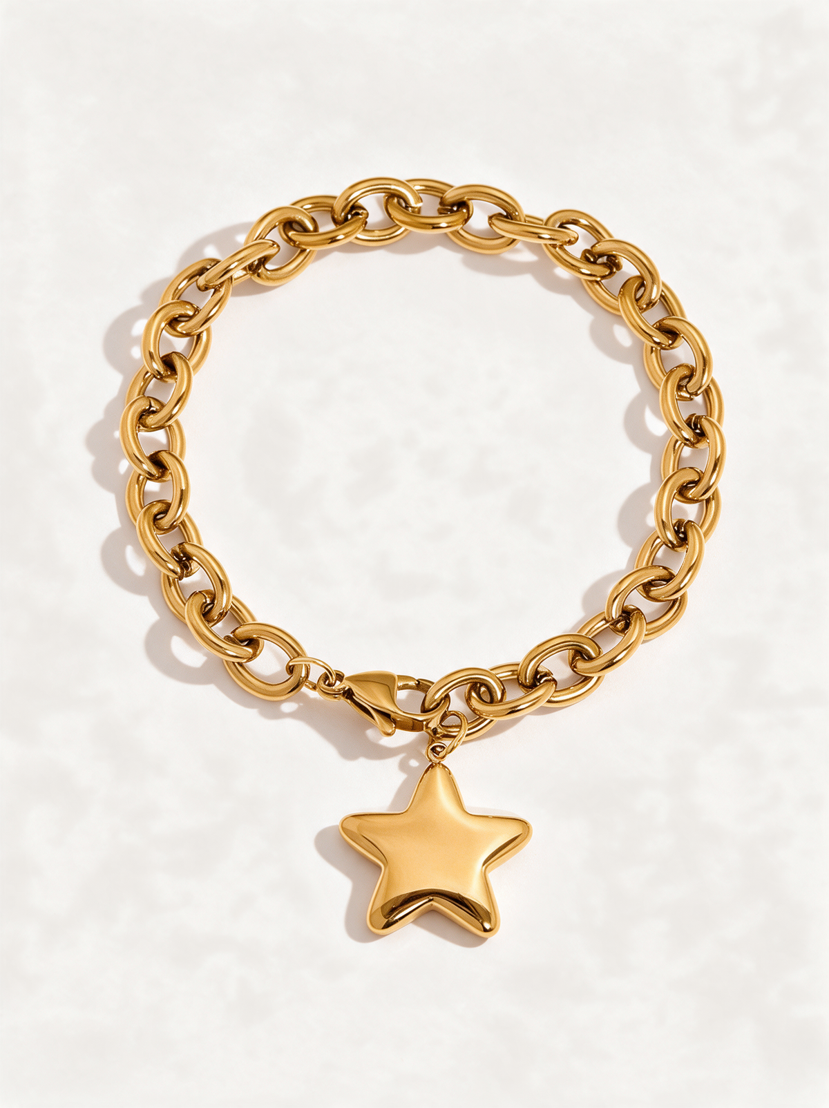 Chunky gold cable chain bracelet with puffy star charm on a neutral background