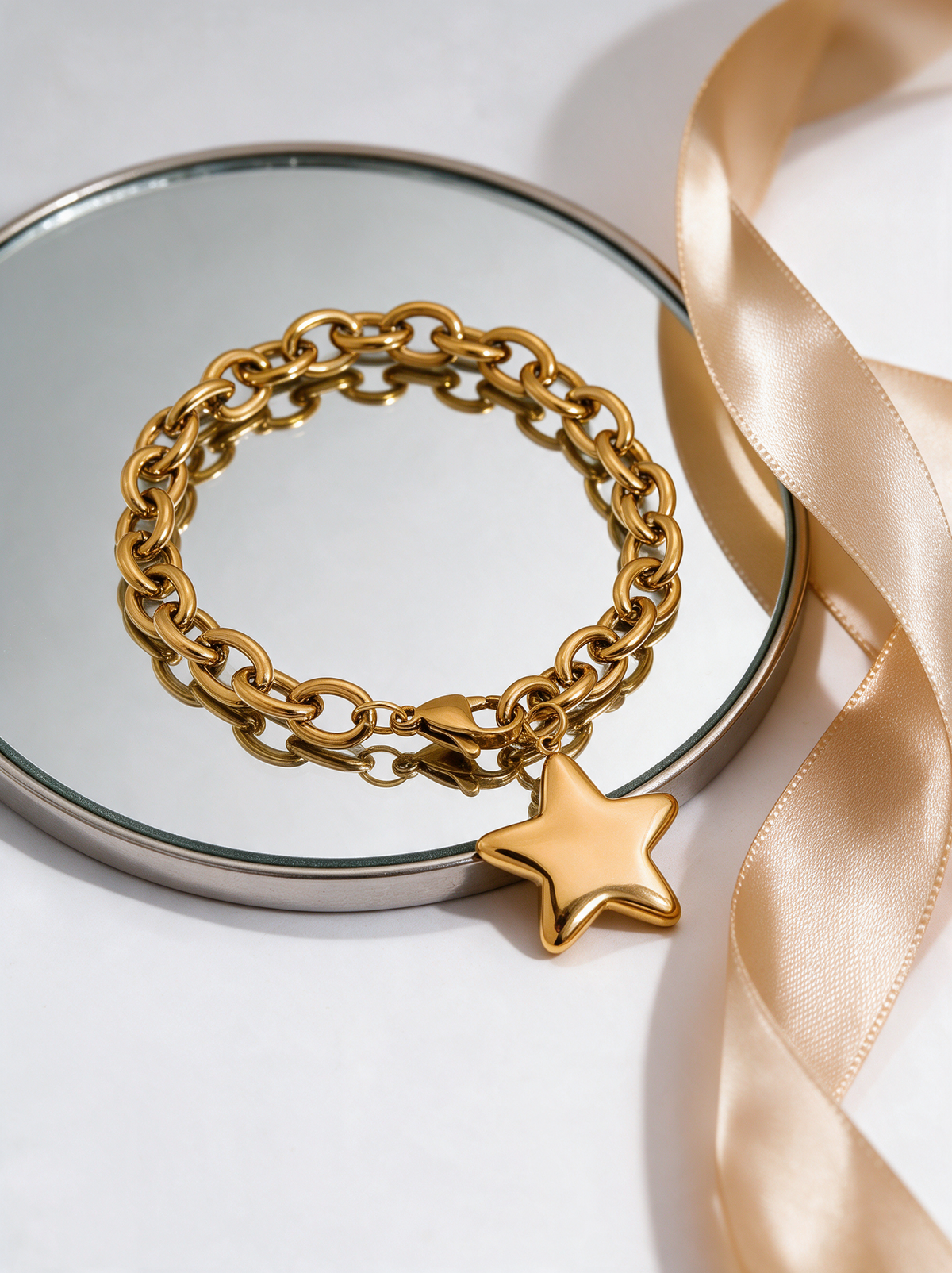 Gold star charm bracelet on a mirror tray with a champagne ribbon