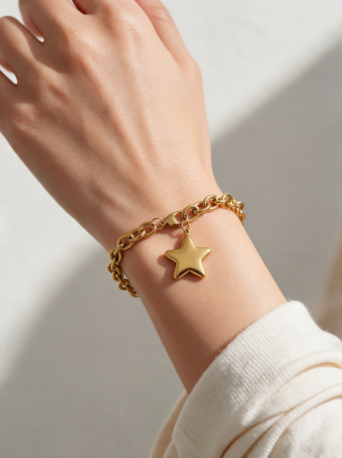 Woman wearing a chunky gold chain bracelet with star charm