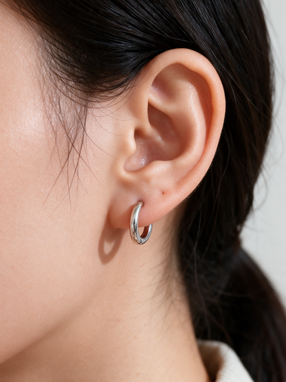 Woman wearing a silver-tone huggie hoop earring