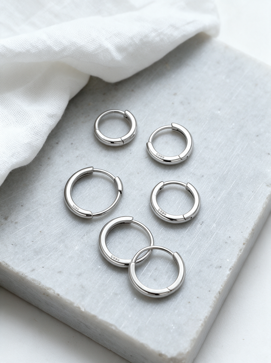 Silver-tone huggie hoops on grey stone with a white linen napkin