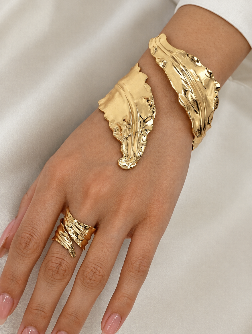 Woman wearing a gold leaf cuff bracelet and wide ring