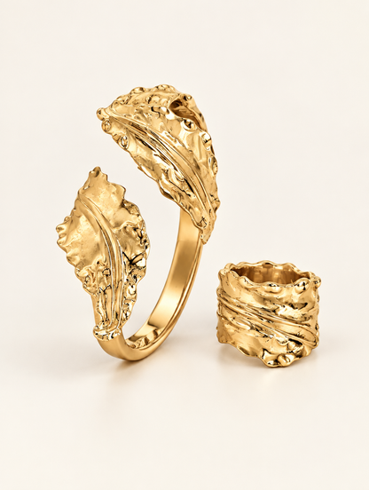 Gold leaf cuff bracelet and wide ring set on a neutral background