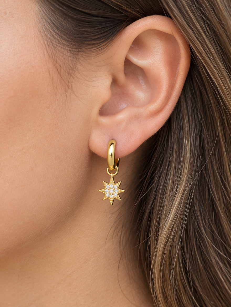 Woman wearing a gold star and moon cz huggie hoop earring