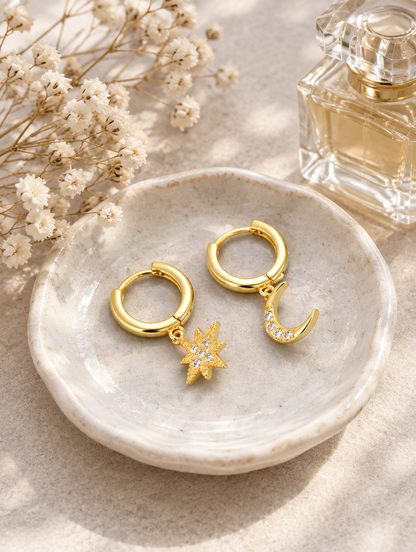 Gold star and moon cz huggie hoops in a styled still life with props