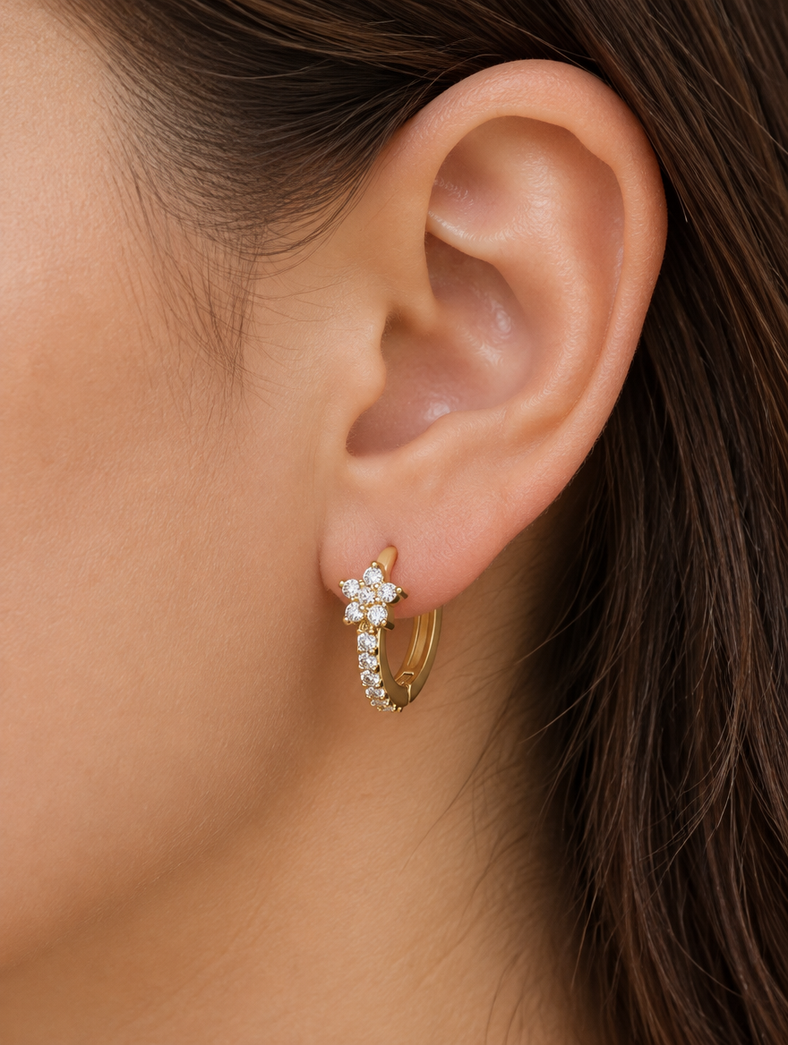 Woman wearing a gold huggie hoop earring with cz flower cluster