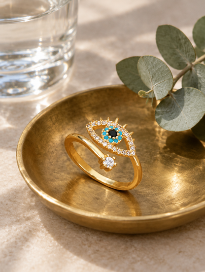 Gold evil eye zirconia ring in a small dish with styling props