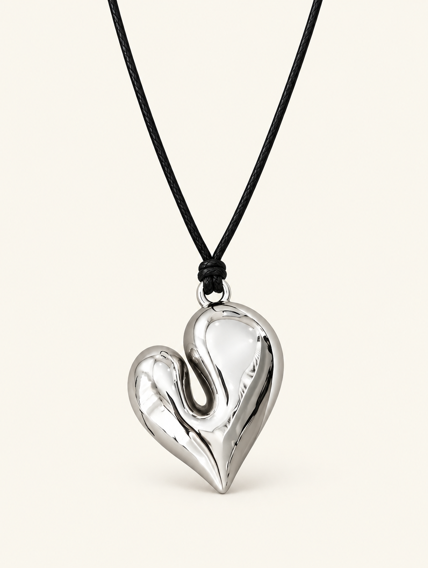 Glossy silver-tone heart pendant on a black cord necklace on a neutral background
