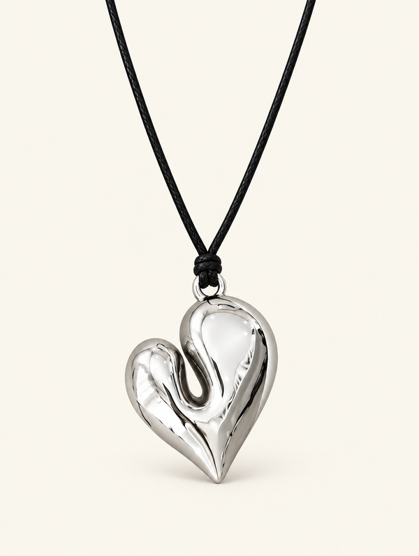 Glossy silver-tone heart pendant on a black cord necklace on a neutral background
