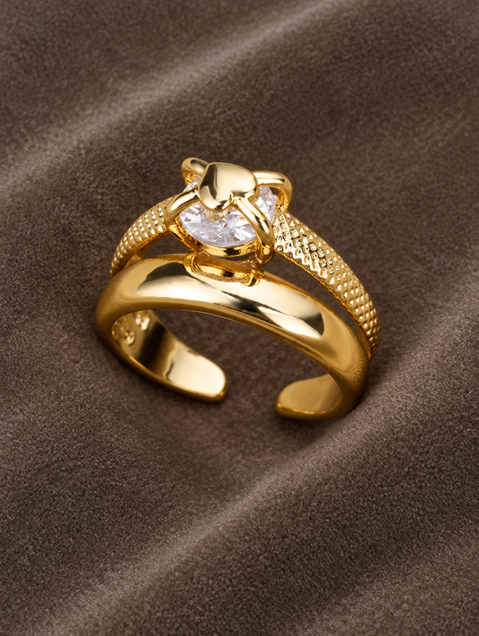 Gold double band zirconia ring resting on a soft textured surface
