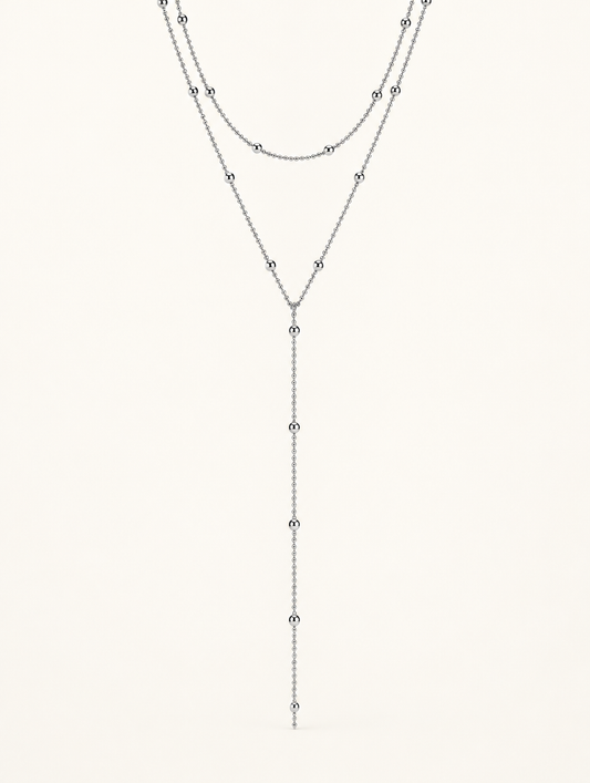Silver-tone two-layer lariat necklace with ball bead chains on a neutral background
