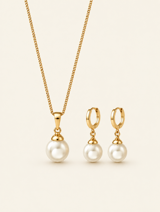 Gold pearl pendant necklace and drop hoop earrings set on a neutral background