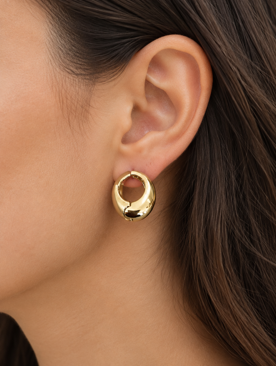 Woman wearing a chunky gold-tone oval hoop earring