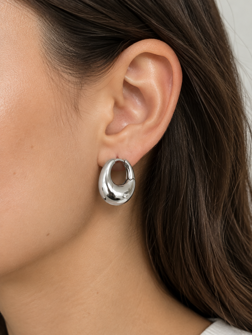 Woman wearing a chunky silver-tone oval hoop earring