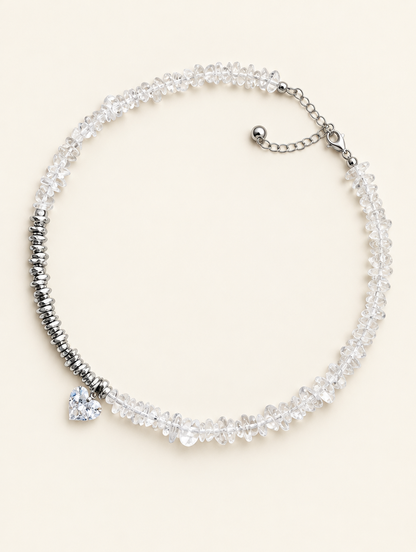Clear chip bead choker necklace with a heart charm and silver-tone spacer beads on a neutral background