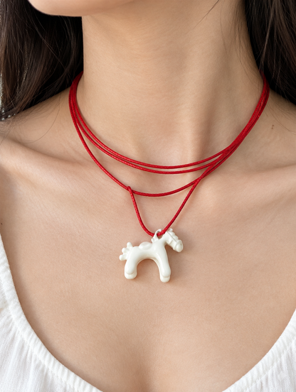 Woman wearing a red cord necklace with a white horse pendant