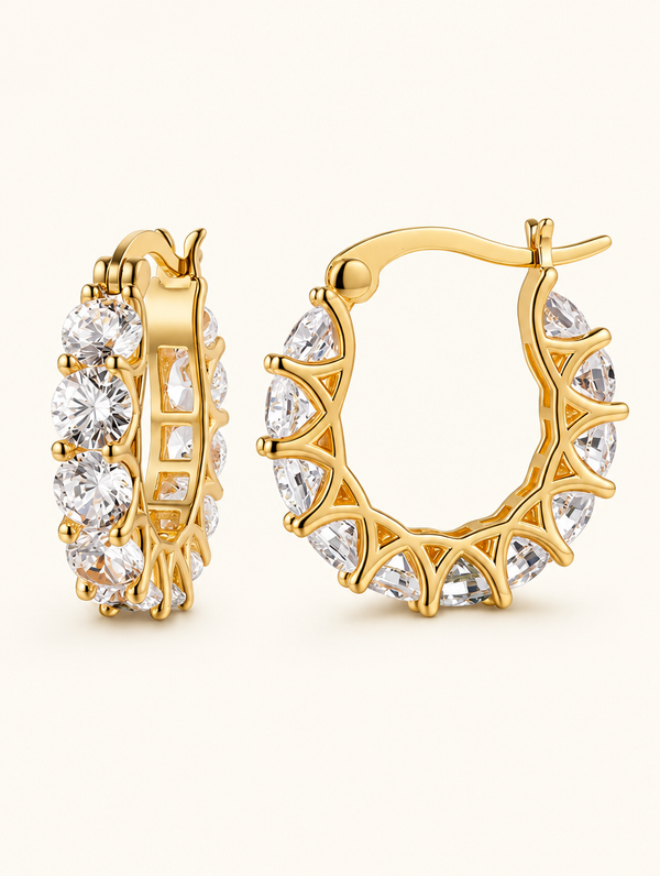 Pair of gold zirconia hoop earrings on a warm off-white background
