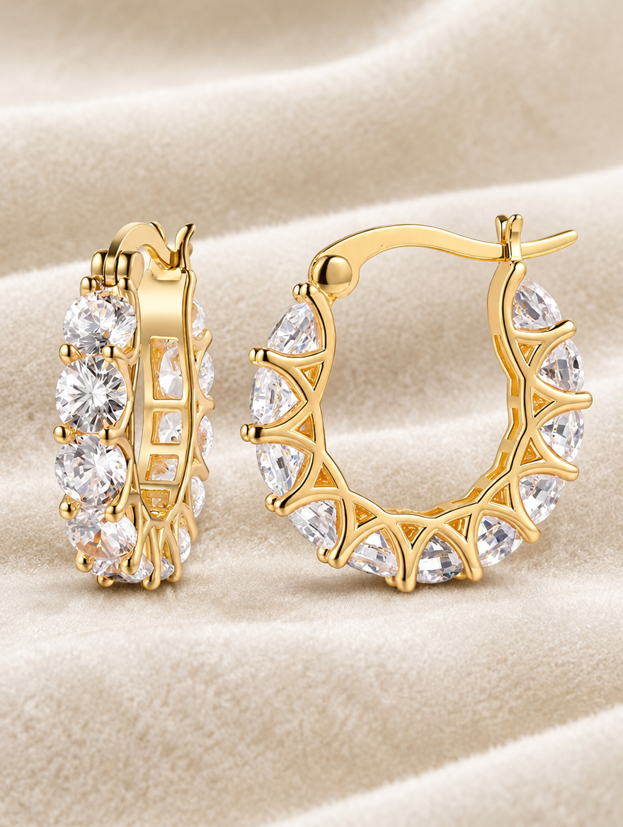 Gold zirconia hoop earrings lying flat on a soft styled surface