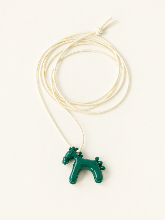 Dark green horse pendant on a cream cord necklace on a neutral background