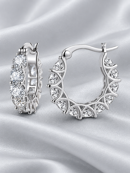 Silver zirconia hoop earrings lying flat on a soft styled surface