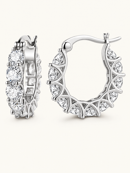 Pair of silver zirconia hoop earrings on a warm off-white background