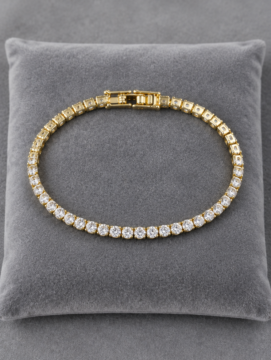 Gold tennis bracelet on a grey velvet cushion