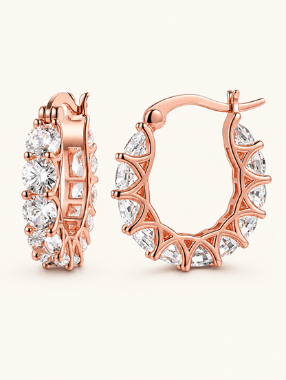 Pair of rose gold zirconia hoop earrings on a warm off-white background