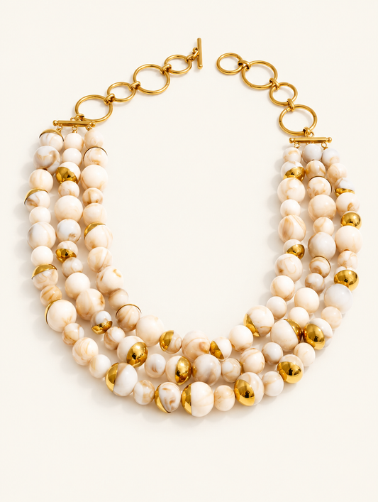 Cream multi-strand beaded collar necklace with gold-tone accents on a neutral background