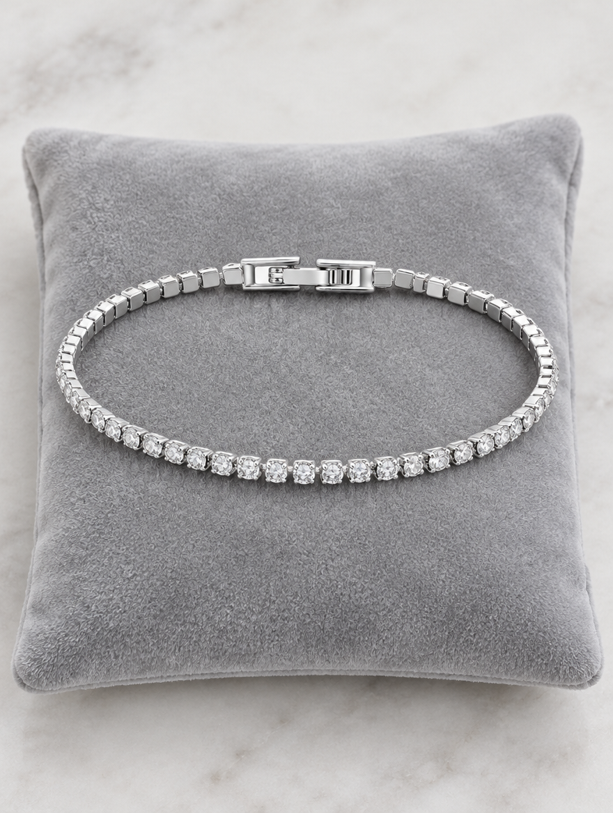 Silver tennis bracelet on a grey velvet cushion