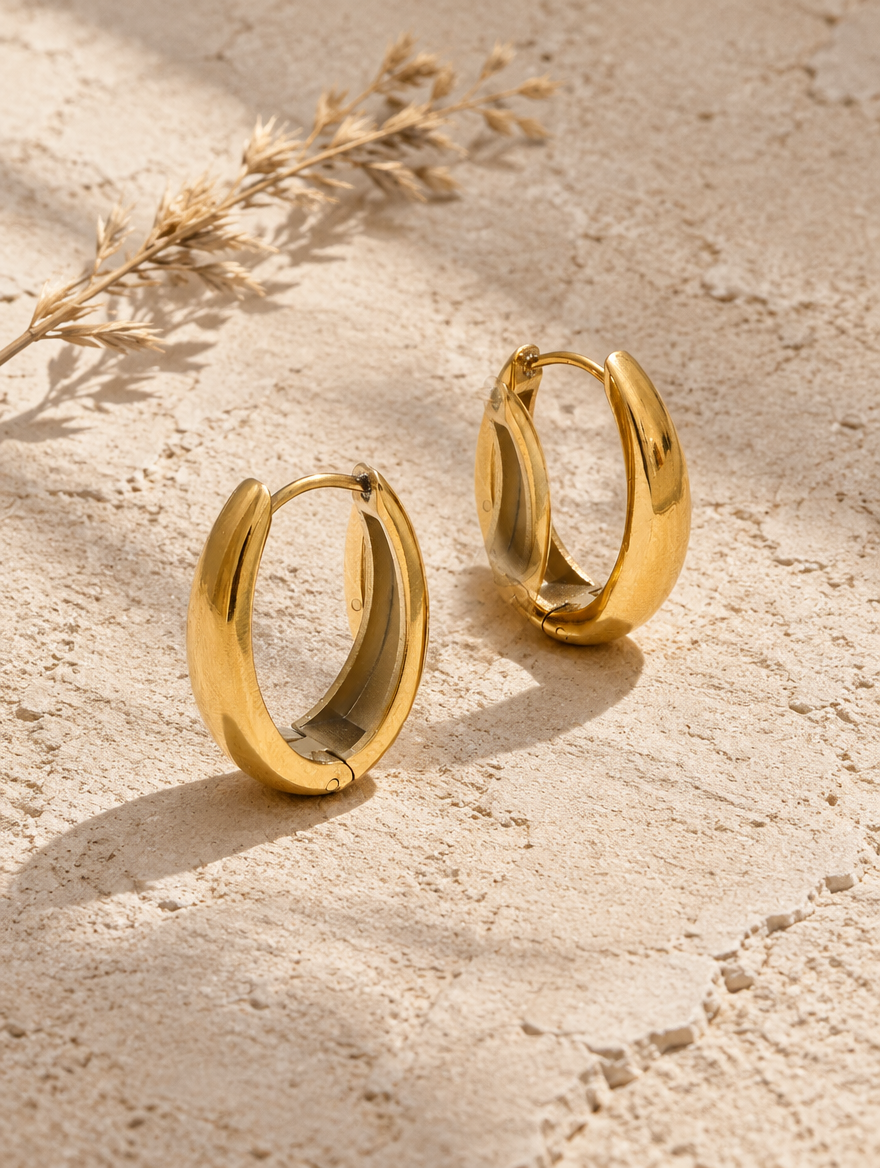 316l steel gold huggie hoop earrings lying flat on a soft styled surface