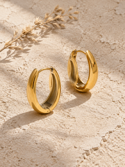 316l steel gold huggie hoop earrings lying flat on a soft styled surface