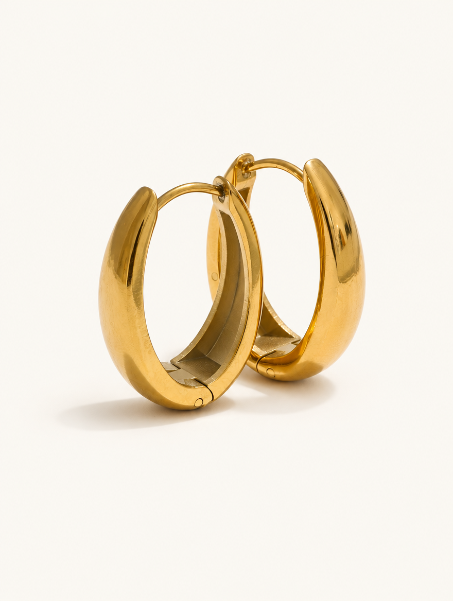 Pair of 316l steel gold huggie hoop earrings on a warm off-white background