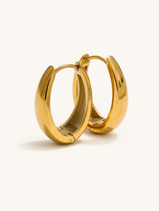 Pair of 316l steel gold huggie hoop earrings on a warm off-white background