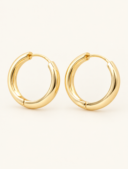 Pair of gold-plated large smooth hoop earrings on a warm off-white background
