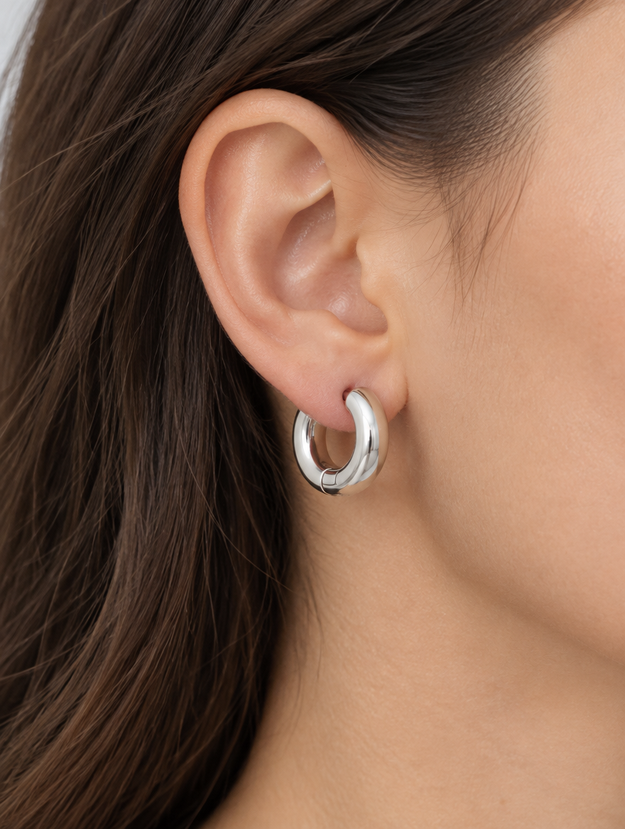 Woman wearing a silver-tone chunky huggie hoop earring