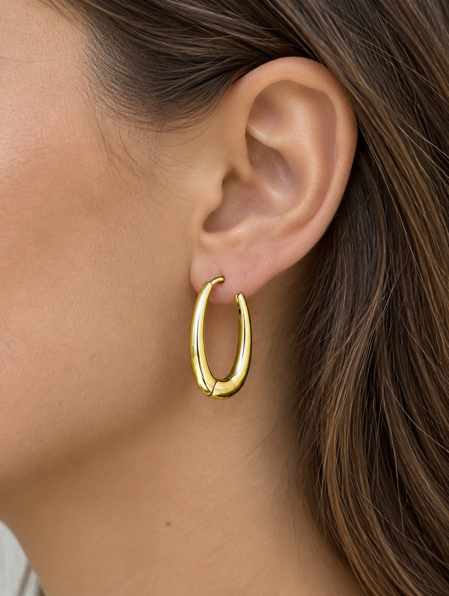 Woman wearing a slim gold-tone elongated oval hoop earring