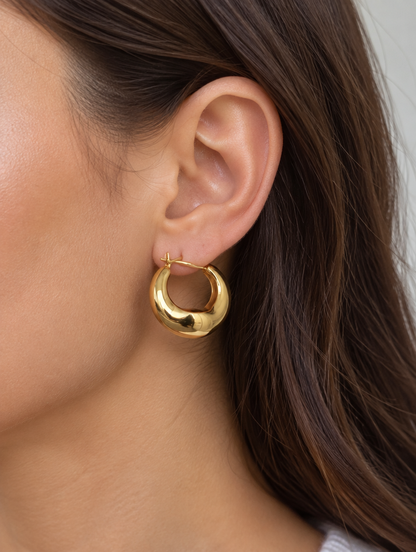 Woman wearing a gold-tone thick rounded hoop earring