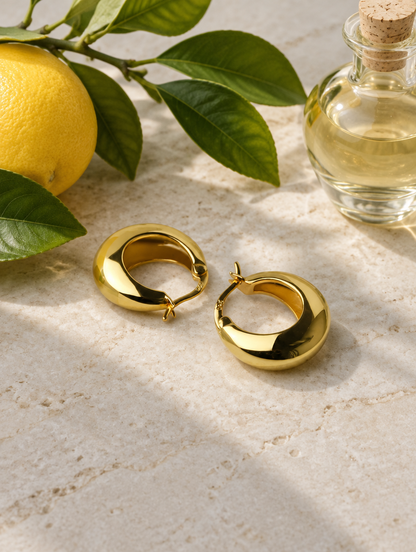 Gold-tone thick rounded hoop earrings in a styled still life with props