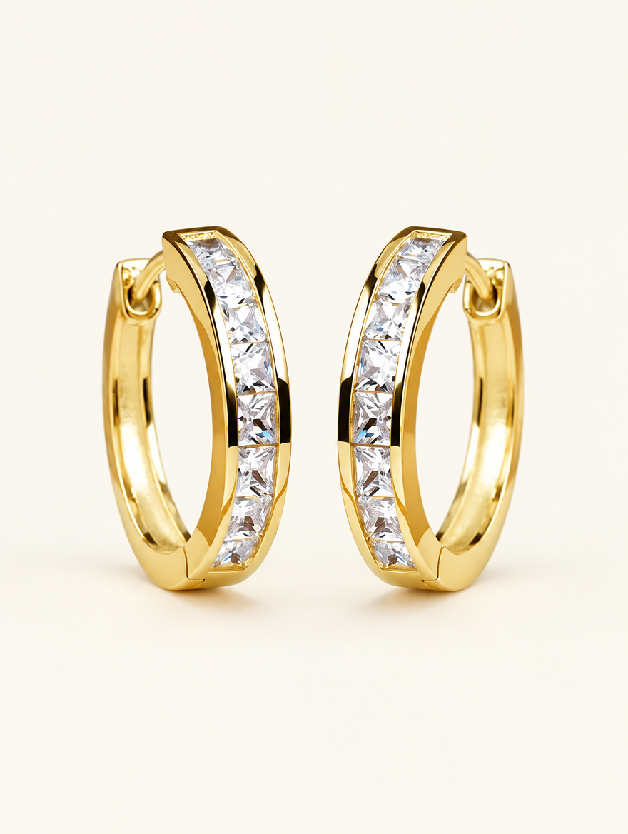 Pair of gold princess-cut zirconia hoop earrings on a warm off-white background