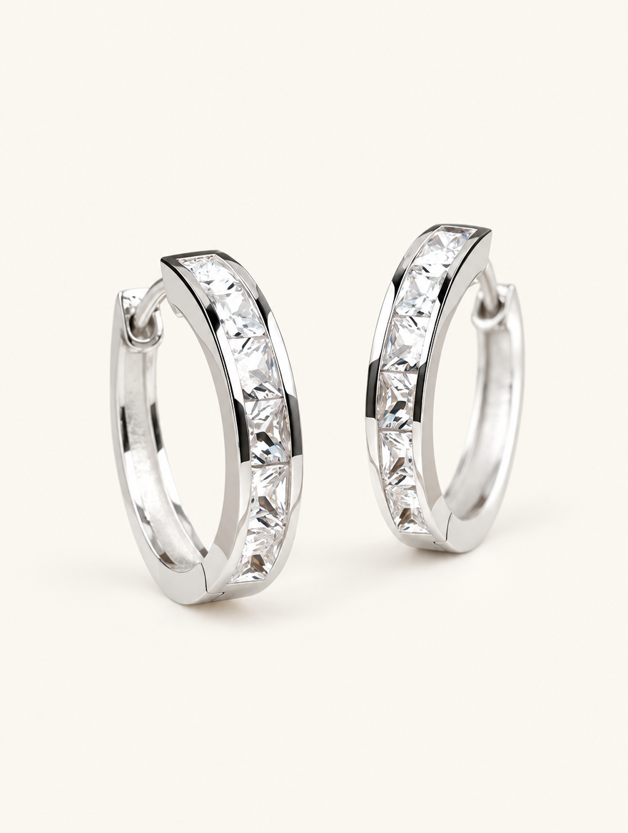 Pair of silver princess-cut zirconia hoop earrings on a warm off-white background