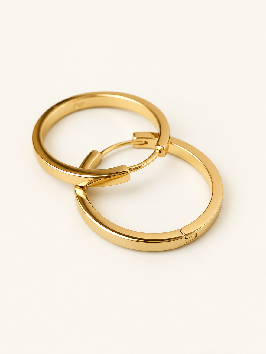 Pair of classic gold-tone round hoop earrings on a warm off-white background
