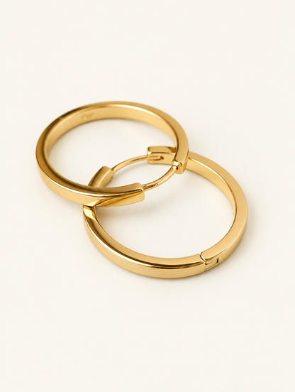 Pair of classic gold-tone round hoop earrings on a warm off-white background