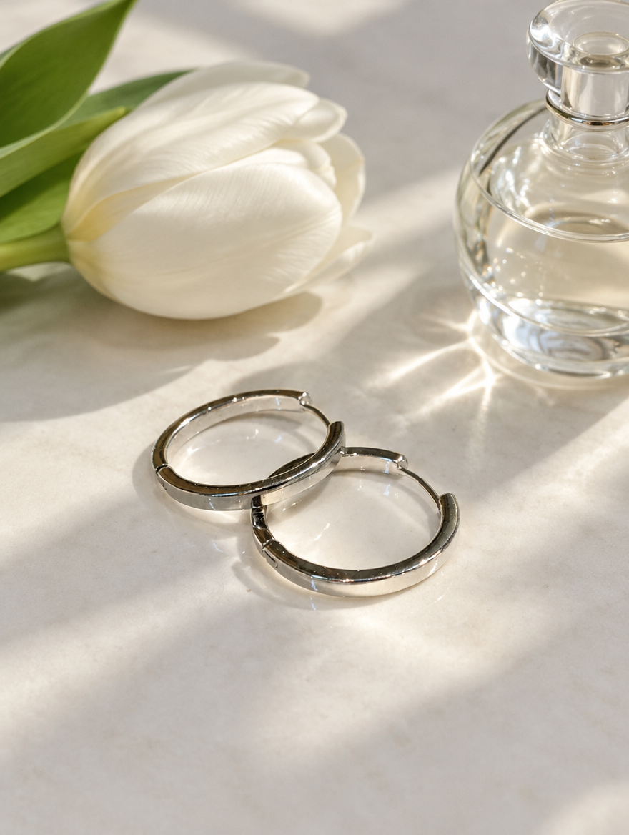 Classic silver-tone round hoop earrings in a styled still life with props