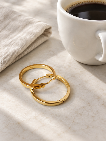 Classic gold-tone round hoop earrings in a styled still life with props